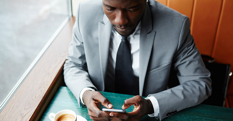 businessman sitting at a table typing on his phone